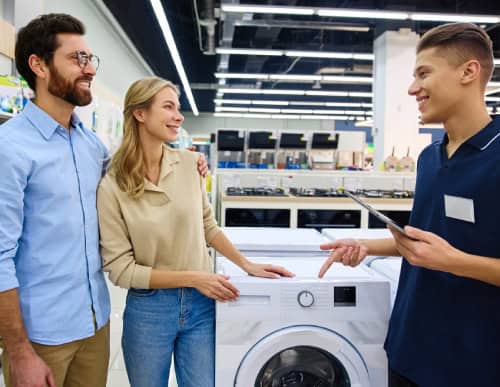 Atendente e clientes conversando sobre máquina de lavar. 