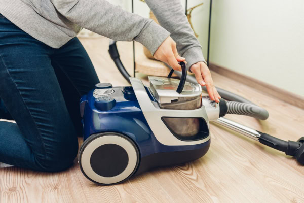 Descubra como limpar aspirador de pó com facilidade! 5 Pessoa puxando reservatório do aspirador de pó para limpar.