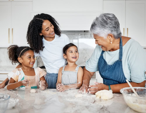 Confira 9 receitas afetivas para o Dia das Mães 1 Mãe, filhos e avó juntos na cozinha, preparando receita.