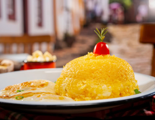 Cuscuz Nordestino: o prato típico com o coração de milhares de brasileiros 1 Cuscuz com queijo e ovo num prato branco.