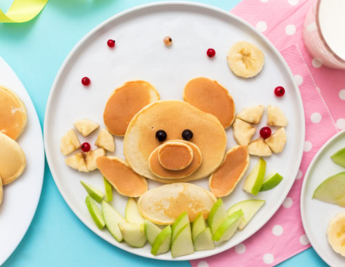 Receitas e ideias de pratos criativos para crianças 1 Prato com panqueca e frutas em formato de urso e flores.