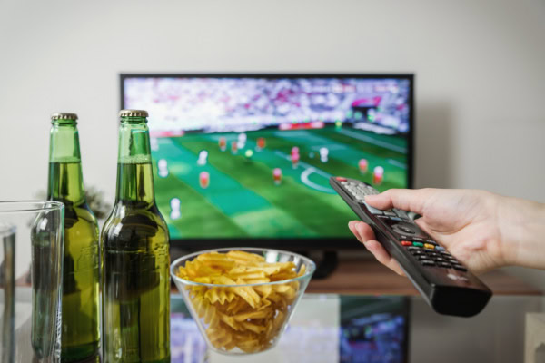 Tamanho de TV ideal: como escolher para cada ambiente 8 Controle apontado pata TV transmitindo jogo de futebol.